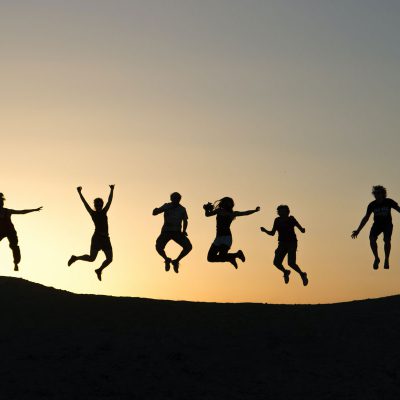 Silhouettes de jeunes sautant sur une colline, à contre-jour