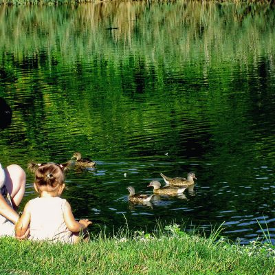 Une femme et une enfant assise près d'un étang